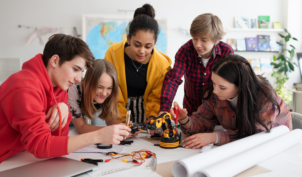 Estudantes montando um braço robótico em sala de aula